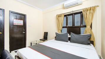 Una habitación de hotel con cama, una silla, una mesa y una puerta con un letrero de 'NO SE PERMITE'.