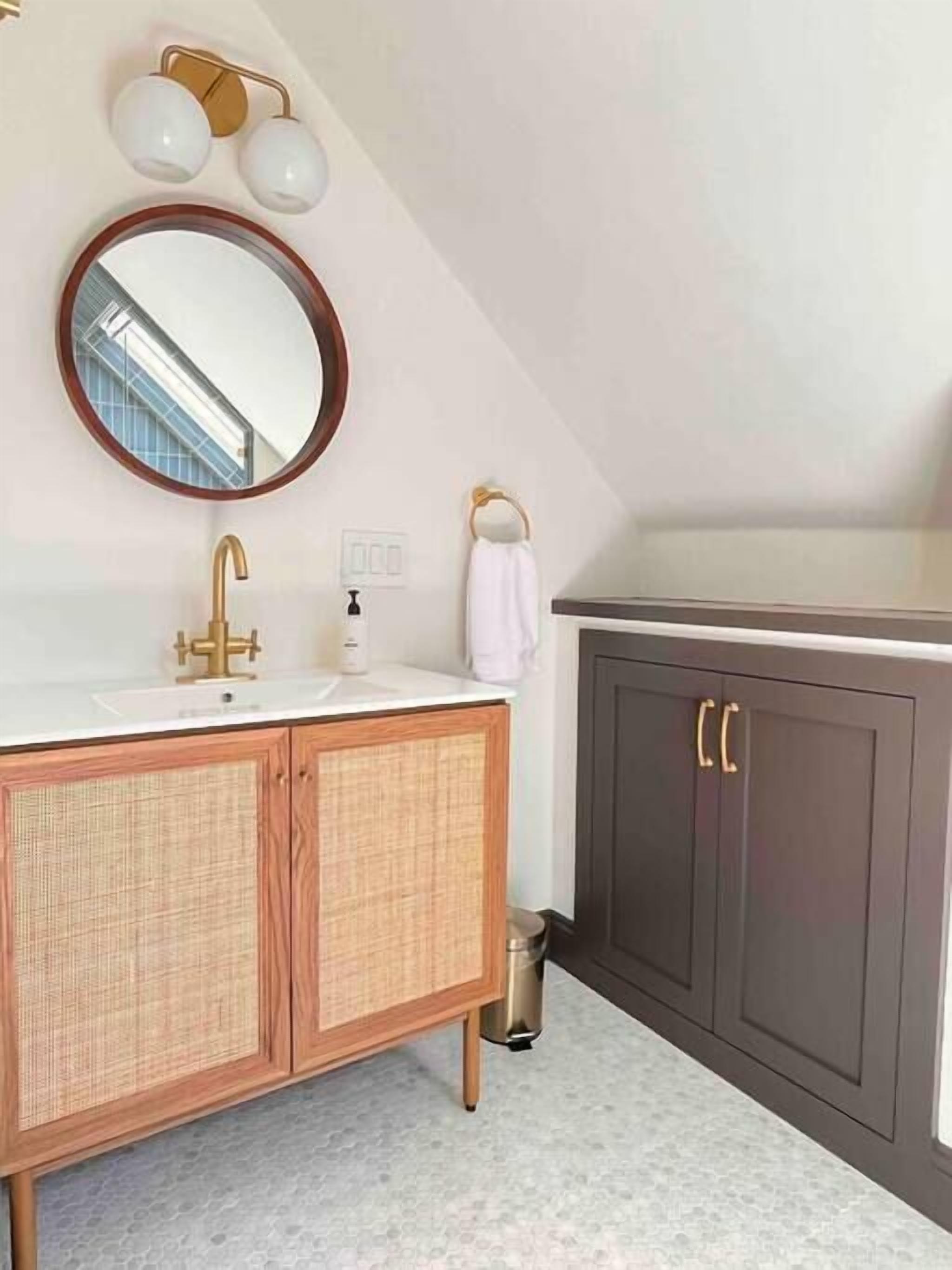 A bathroom with a vanity, a mirror, a towel rack, and a trash bin.