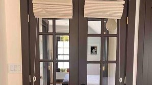 A dark wooden double door with glass panels, a white rug on the floor, and a glimpse of a bedroom with a bed and a framed picture on the wall. - Modern Victorian in the heart of downtown Nevada City (Nevada City)