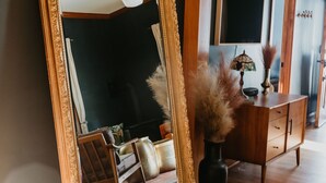 A room with a large ornate mirror, a wooden cabinet, and a vase with dried plants. - Modern Victorian in the heart of downtown Nevada City (Nevada City)