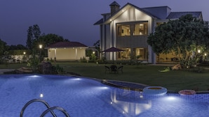 Ein modernes Haus mit Pool, Gartenmöbeln und einer gut beleuchteten Terrasse.