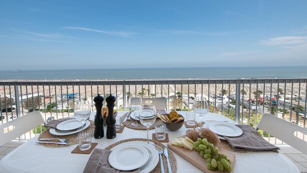 Une table dressée pour un repas, avec vue sur la mer et la plage.