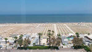 Une plage bordée de rangées de parasols et de chaises longues, un espace de stationnement et une vue sur l’océan.
