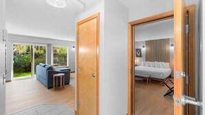 Ein modernes Interieur mit einer Holztür, die in ein Schlafzimmer mit Bett und Nachttischen führt.