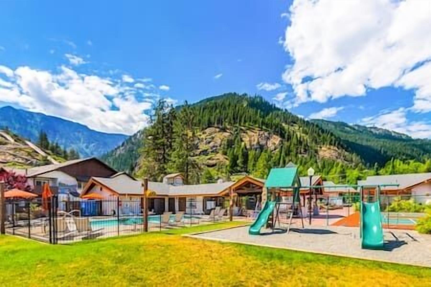 Ein Resort mit Außenpools, Wasserrutschen und Hütten mit Bergblick.
