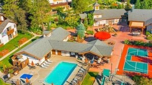 An aerial view of a residential area with a swimming pool, tennis court, and multiple houses. - Icicle Village 2-Bedroom w/ Pool (Leavenworth)