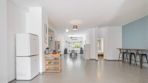Une cuisine moderne avec des appareils électroménagers blancs, une table en bois et un coin bar avec des chaises.