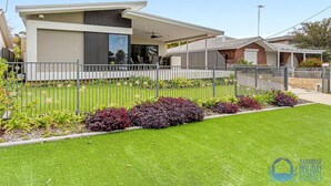 A modern two-story house with a well-maintained lawn and decorative plants. - Water Lovers Haven in Mandurah (Halls Head)