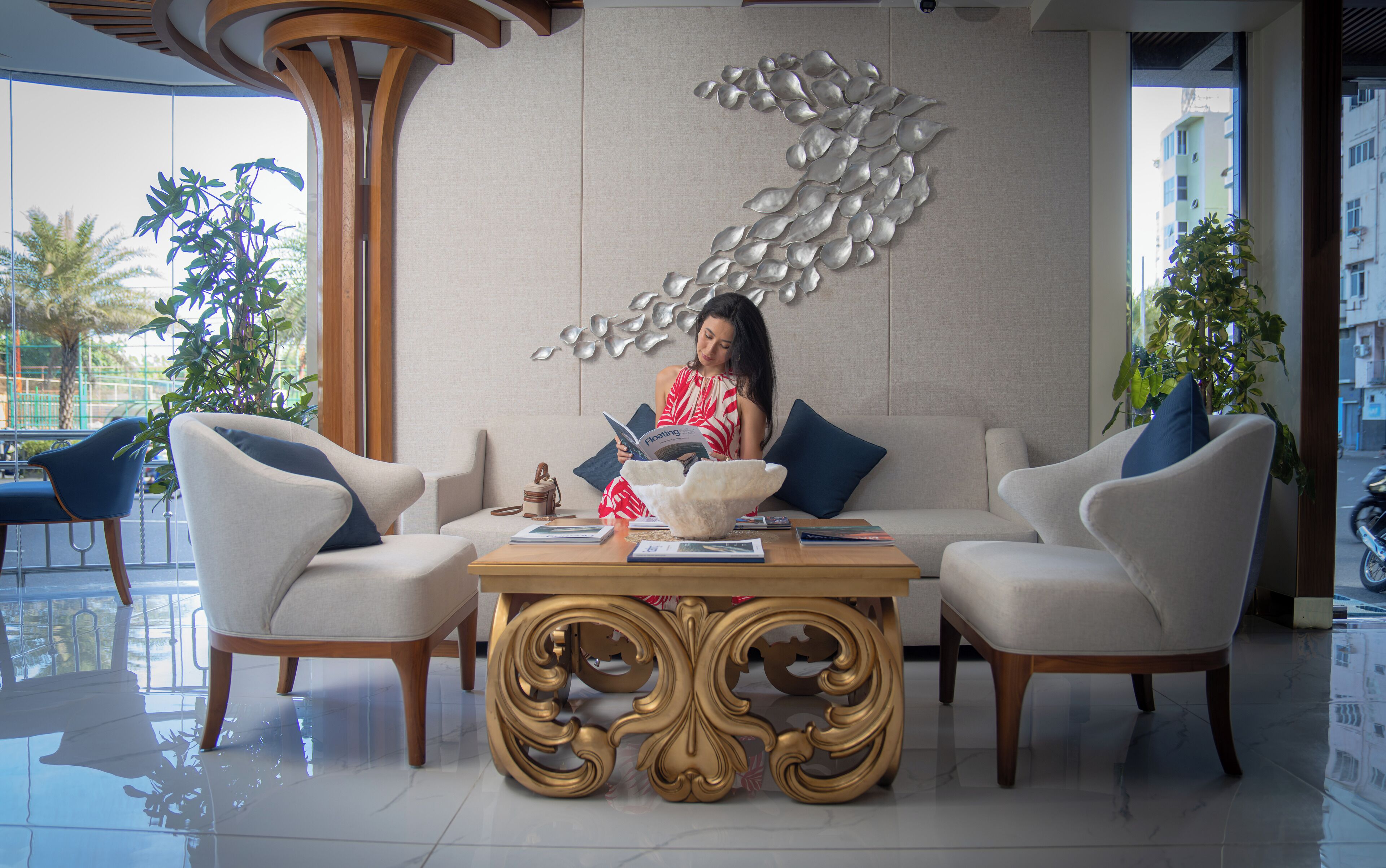 A modern lounge area with a sofa, two armchairs, a decorative table, and a wall art piece.