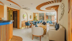 A modern hotel lobby with a reception desk, seating area, and large windows offering a view of the outside.