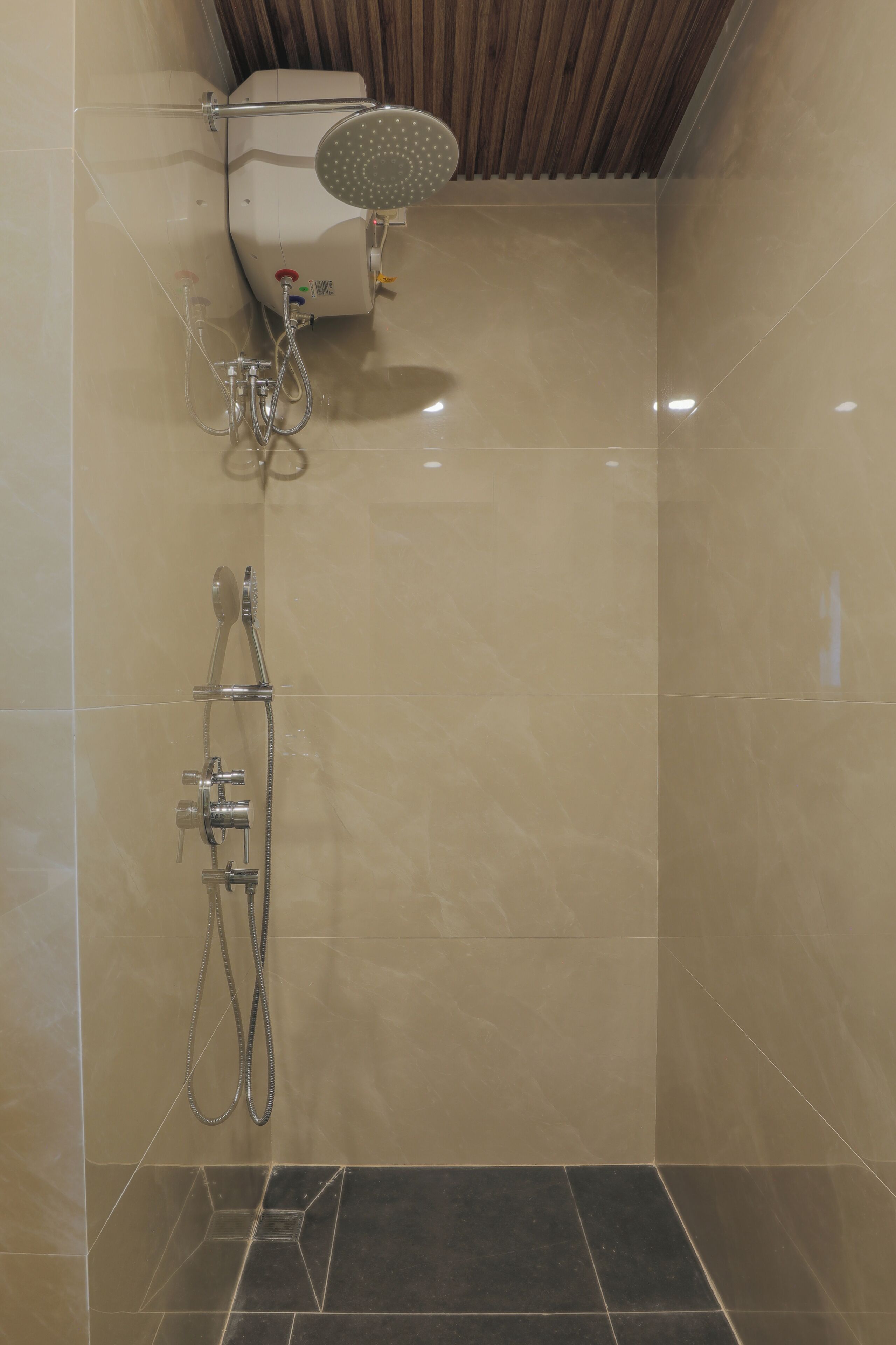 A shower area with a handheld showerhead, a wall-mounted faucet, and a control panel.