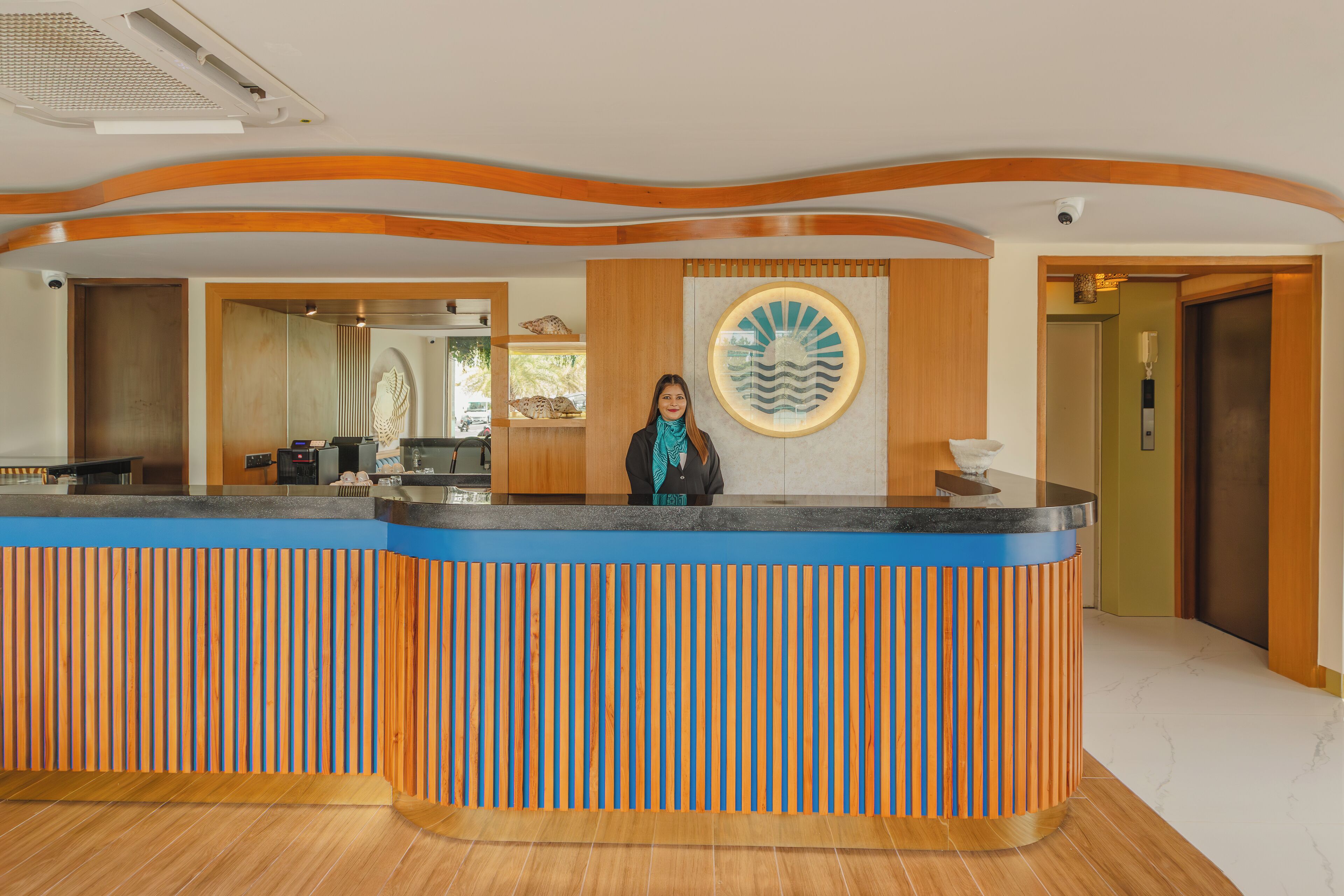 A reception desk with a blue and orange design, a wooden floor, and a wall-mounted decorative piece.