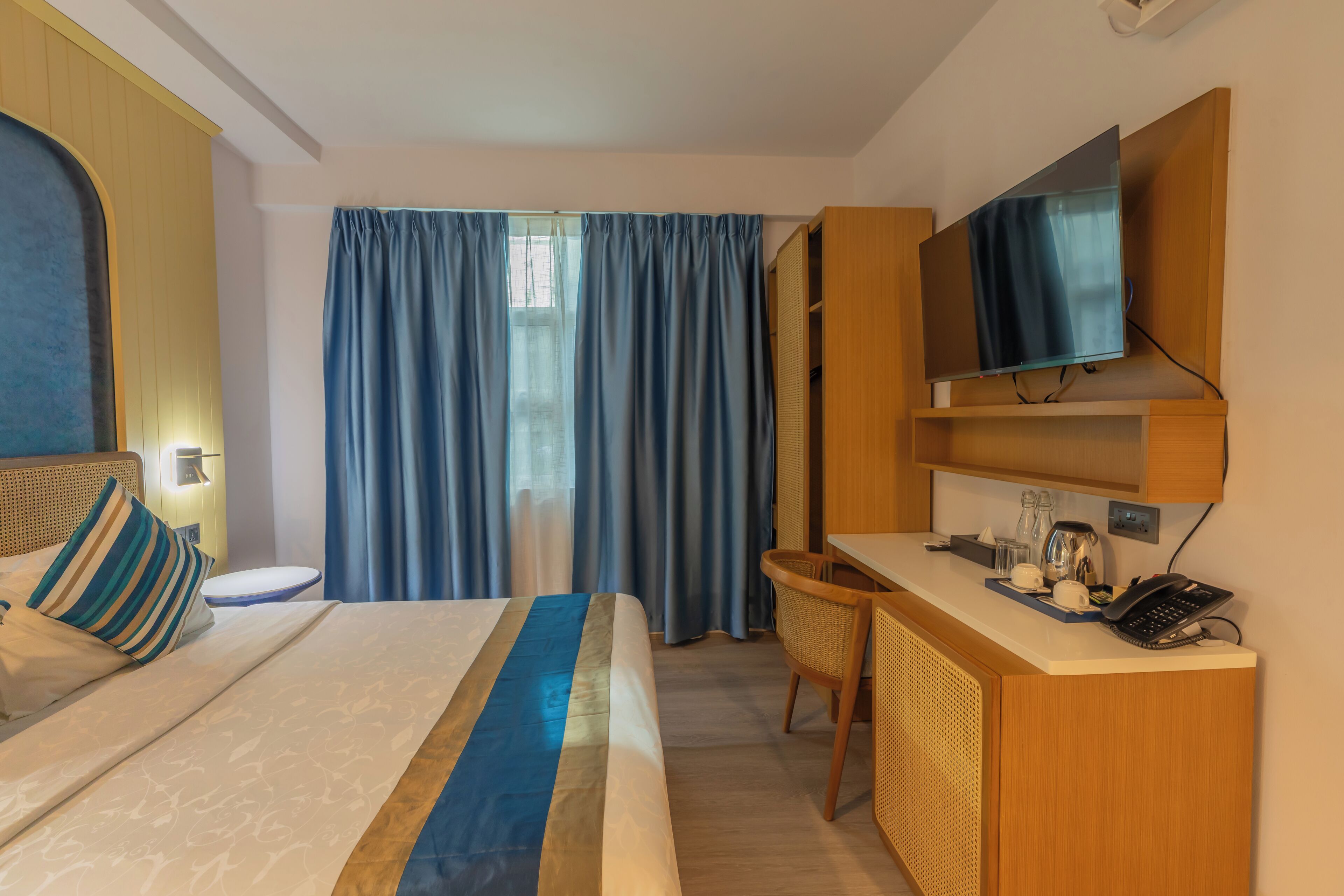 Una habitación de hotel con cama, escritorio, silla, televisión y teléfono.