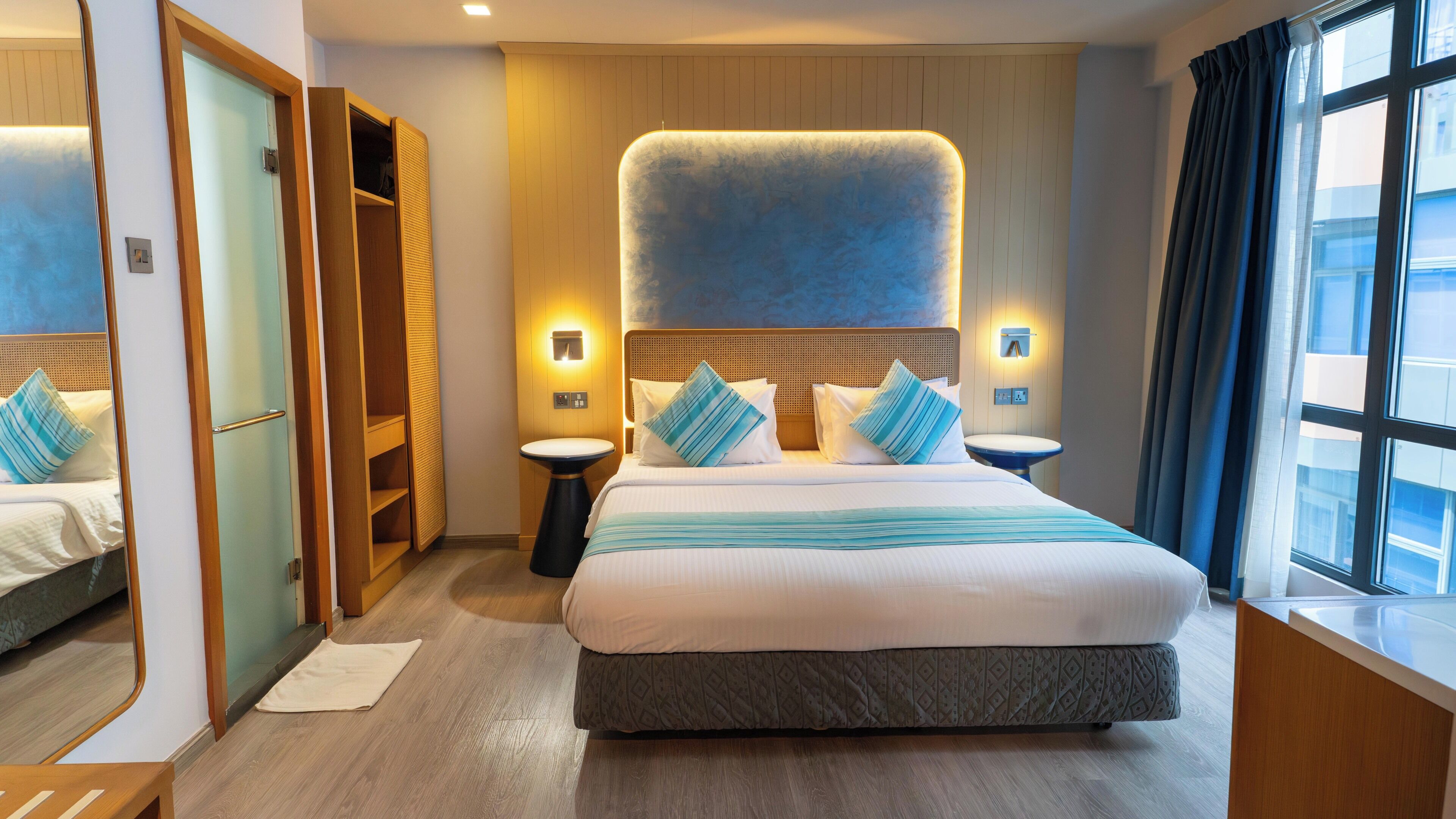 Une chambre d’hôtel avec un grand lit, une armoire, une table de chevet et une fenêtre.