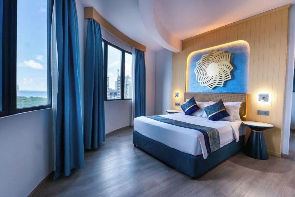 Une chambre d’hôtel moderne avec un grand lit, une vue sur la ville et un élément décoratif mural.