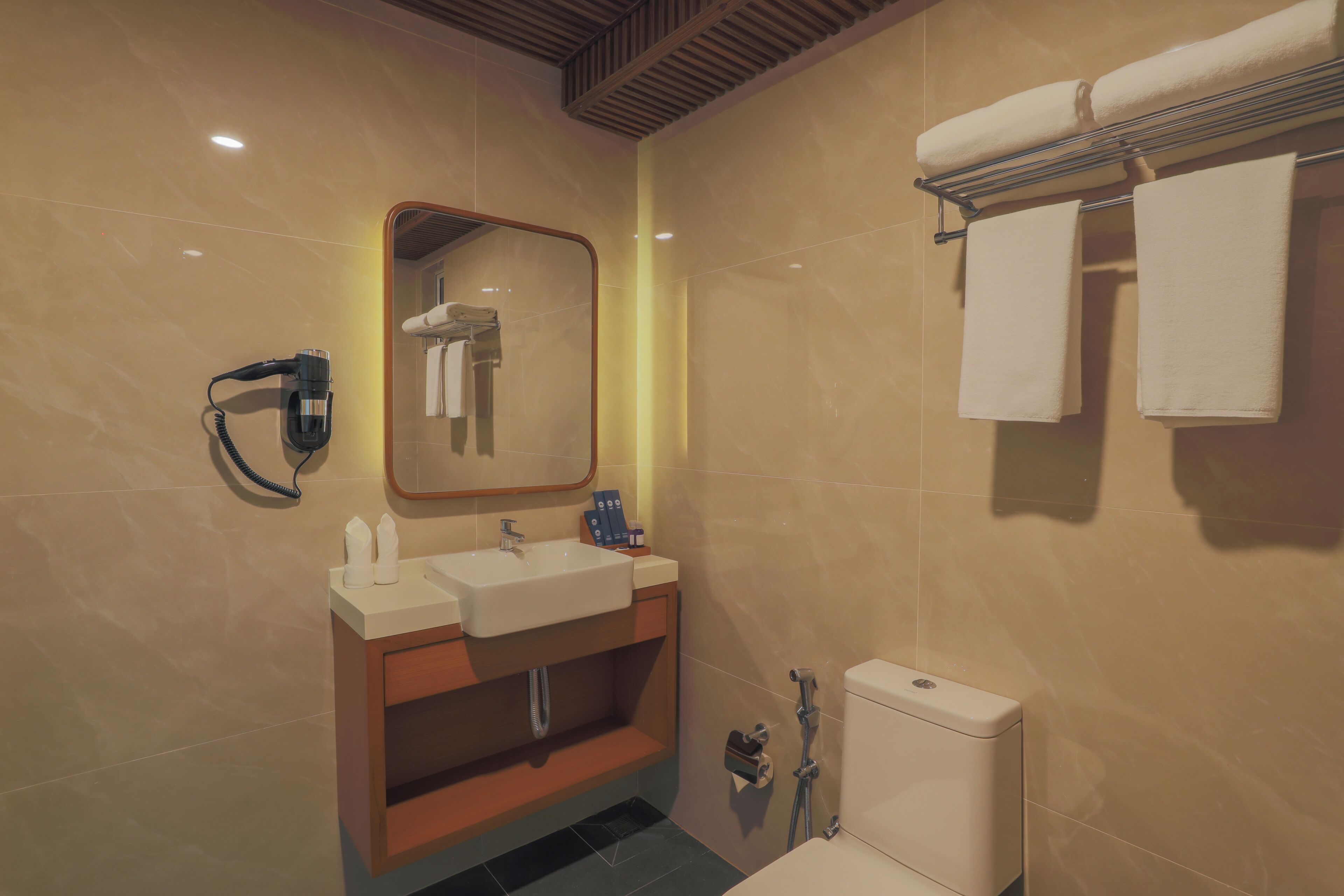Une salle de bain moderne équipée d’un lavabo, d’un miroir, d’un porte-serviettes et de toilettes.