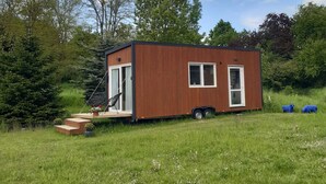 Une petite cabane en bois d’un seul étage, dotée d’une porte coulissante et d’un petit espace porche.