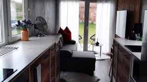 Une cuisine compacte comprenant un coin repas, un petit espace salon et une vue sur l’extérieur.