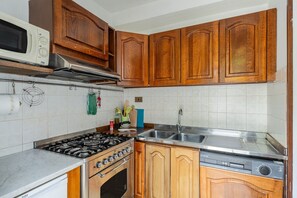 Una cocina con armarios de madera, microondas, estufa y lavavajillas.