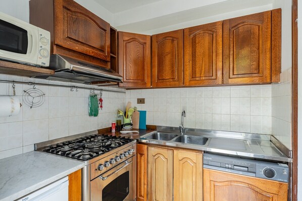 Une cuisine avec des meubles de rangement en bois, un four à micro-ondes, une cuisinière et un lave-vaisselle.