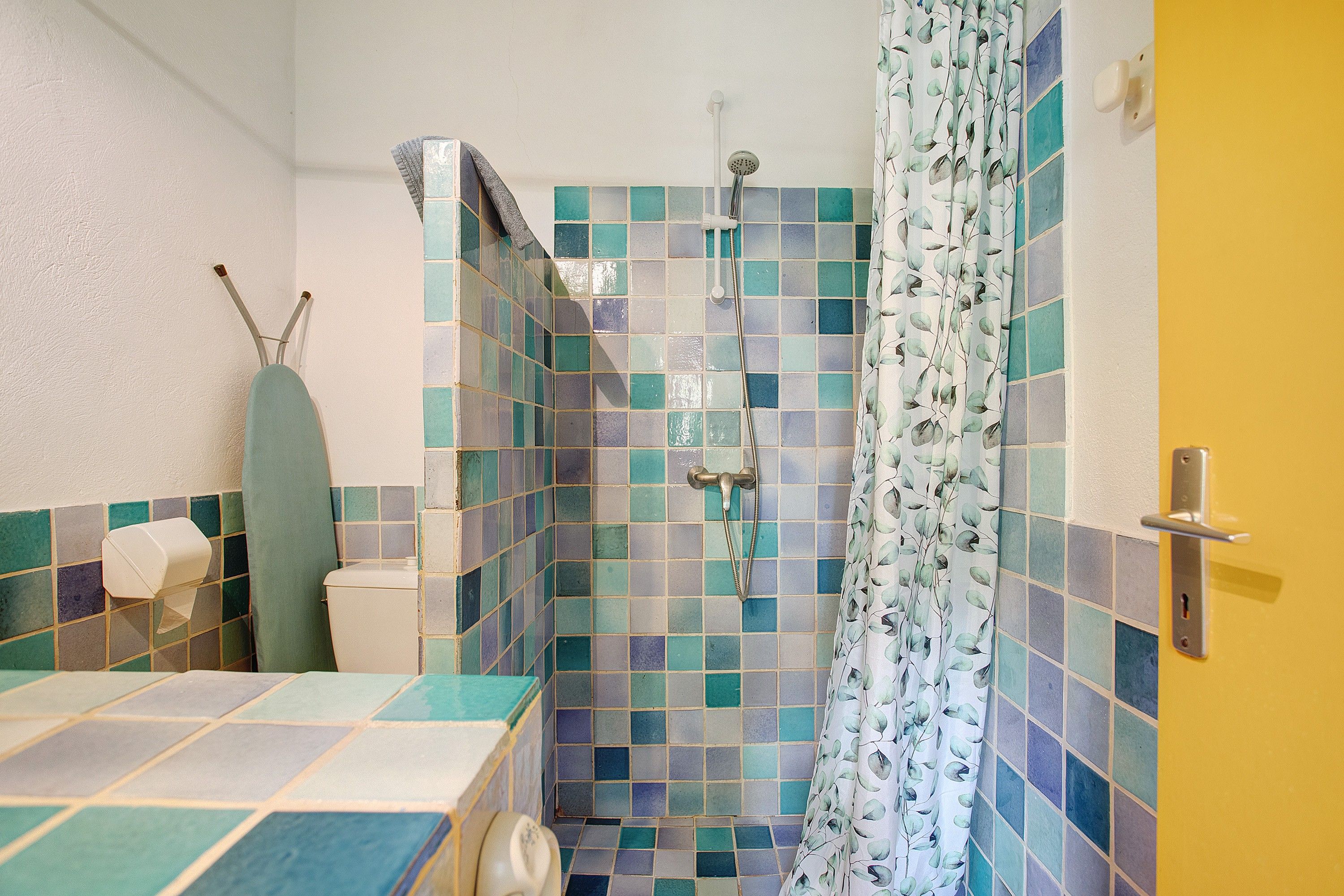 A bathroom with a shower, toilet, and a towel rack.