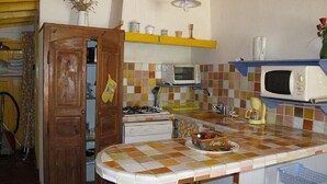 A kitchen with a checkered tile backsplash, a microwave, a stove, and a sink.