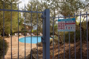 A fenced swimming pool area with a sign detailing pool regulations and a small pool. - Studio Apartment 'Meublé' with Shared Pool, Private Garden and Wi-Fi (Lorgues)