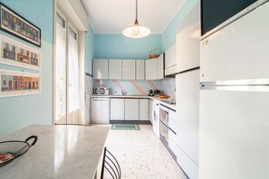 Una cocina con armarios blancos, microondas, fregadero y refrigerador.