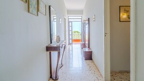 Un couloir orné de tableaux encadrés, une console en bois et une porte donnant sur un espace extérieur.