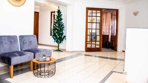 Uma sala de estar moderna com um sofá cinzento, uma mesa de centro, um pinheiro de Natal e uma porta de madeira.