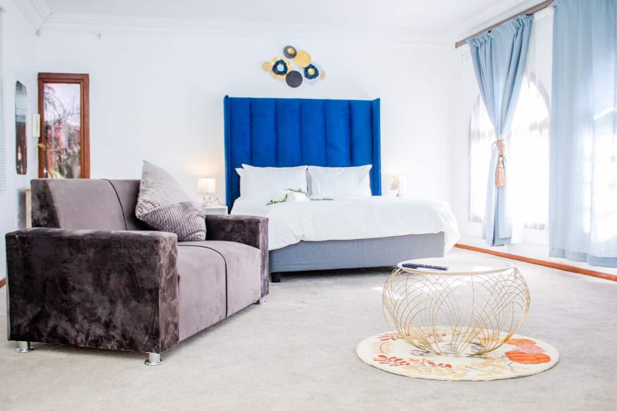 Une chambre à coucher moderne avec une tête de lit bleue, un canapé gris et une table basse ronde.