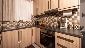 A kitchen with wooden cabinets, a black oven, a coffee maker, and a checkered backsplash. - Koukounaria House Holiday Home with Private Pool, Wi-Fi, and Air Conditioning (Zakynthos)