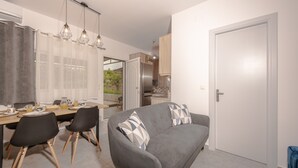 A modern kitchen with a dining area, a grey sofa, and a door leading to another room. - Koukounaria House Holiday Home with Private Pool, Wi-Fi, and Air Conditioning (Zakynthos)