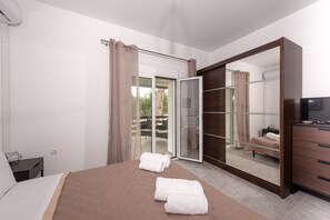 Una camera da letto con un letto, un armadio, una televisione e una porta scorrevole in vetro che dà su una zona esterna.