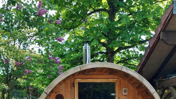 A wooden barrel-shaped structure with a door, a small bench, and a chimney.