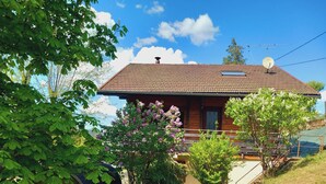 A wooden house with a tiled roof, a satellite dish, and a small porch.