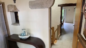 Un pasillo con un letrero de piedra que dice 'Kamen St.' y un cuenco de vidrio sobre una consola oscura.