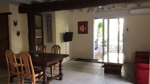 Un comedor con una mesa y sillas de madera, un televisor montado en la pared y un sofá rojo en la esquina.