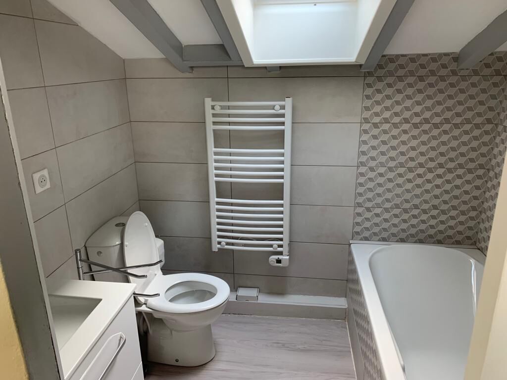 A compact bathroom with a toilet, a white sink, a bathtub, and a towel rack.
