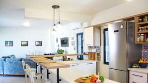 A modern kitchen with a central island, bar stools, and a built-in refrigerator. - Villa Stefania with Pool (Rethymno)