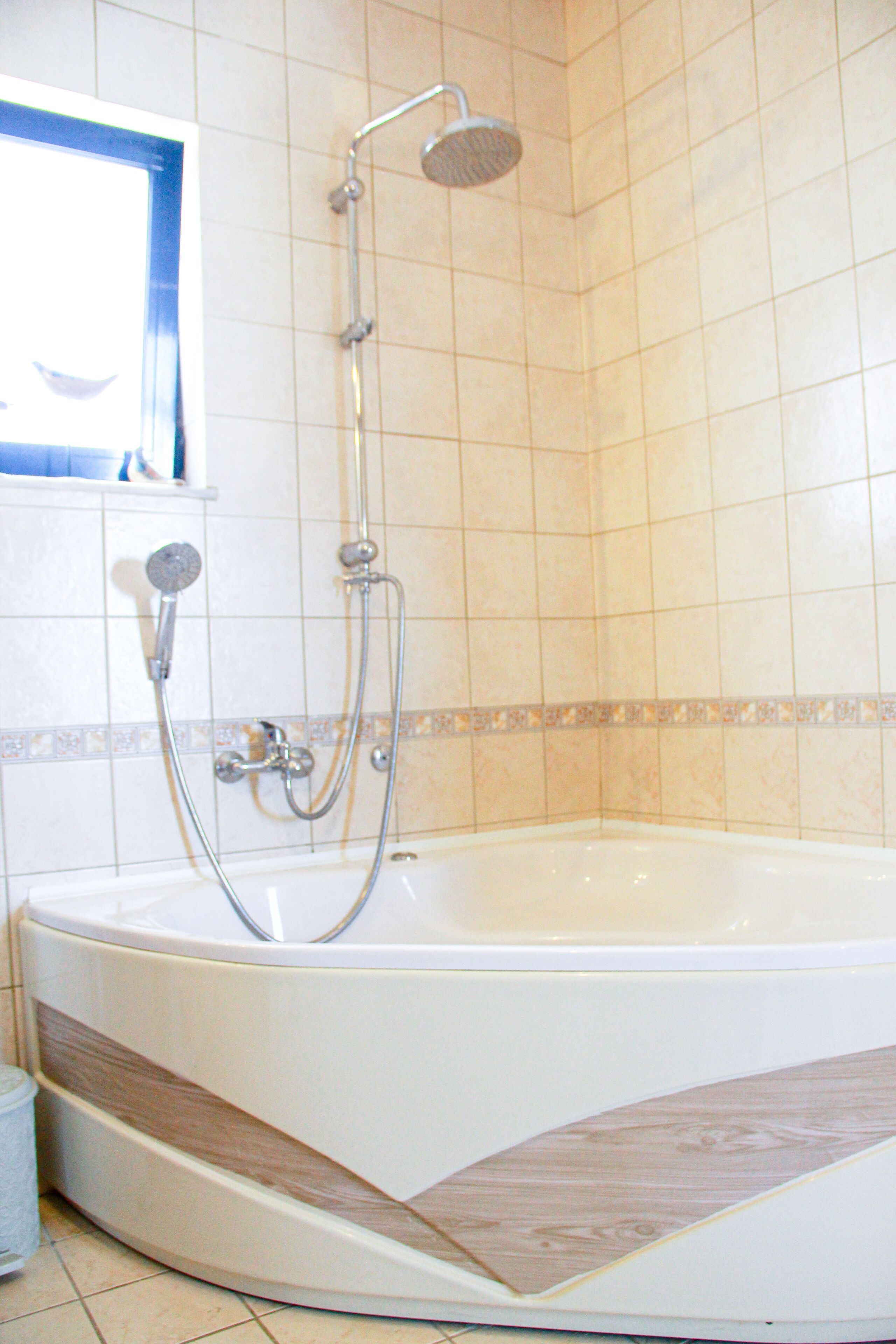 A bathroom with a bathtub, a shower, and a window.