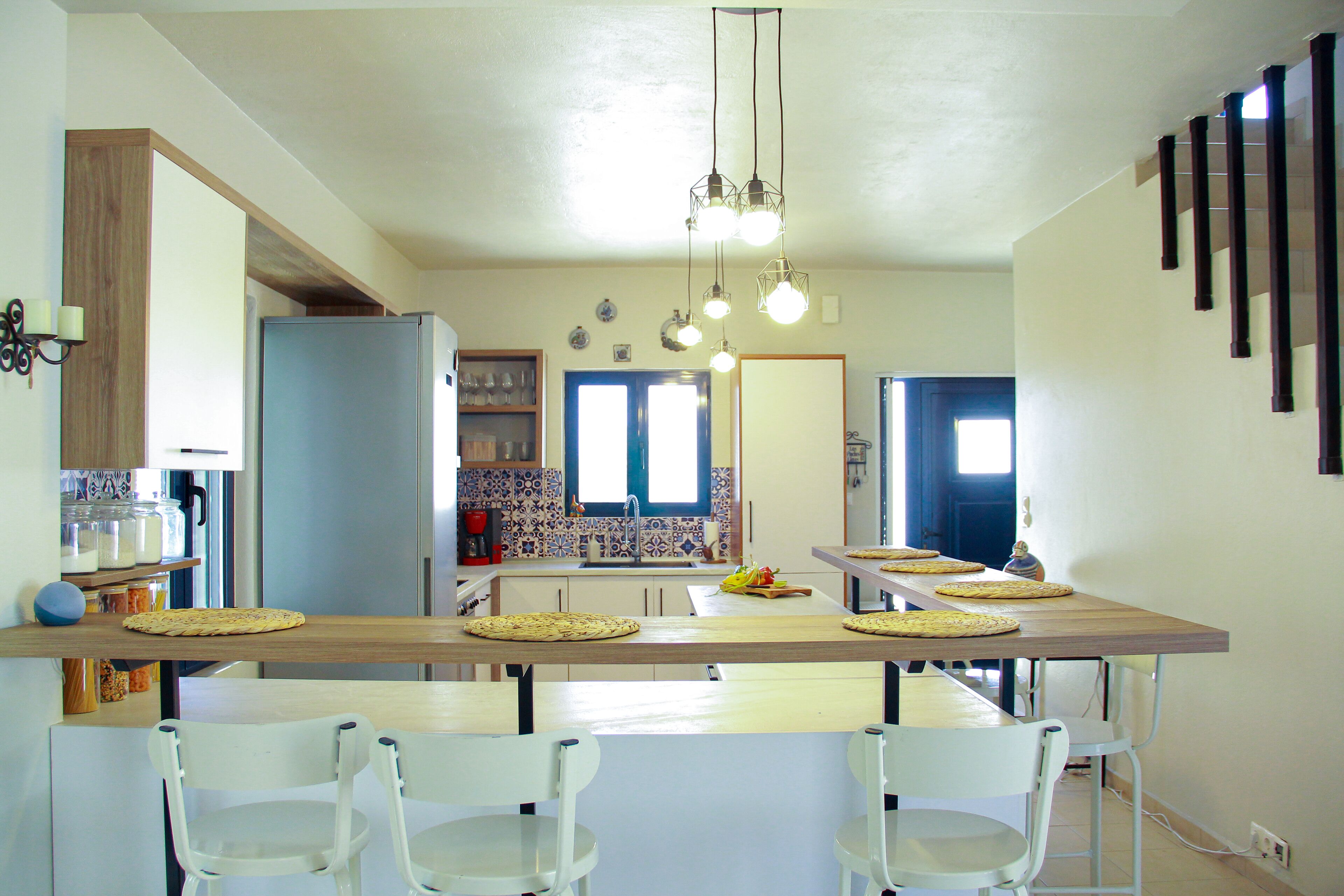 Una cocina moderna con una isla central, sillas blancas y una mesa de comedor para cuatro.