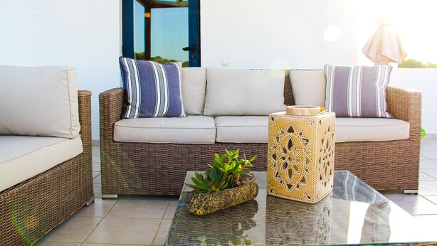 A wicker sofa with cushions, a glass coffee table with a plant, and a decorative box. - Villa Stefania with Pool (Rethymno)