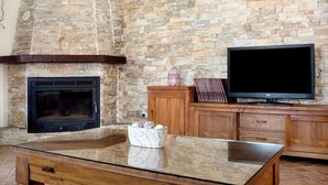 Une cheminée en pierre, un téléviseur à écran plat et des meubles en bois dans un salon.