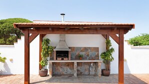 Une cuisine extérieure dotée d’un mur de fond en pierre, d’une pergola en bois et de plantes en pot.
