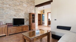 Un salon avec un mur en pierre, des meubles en bois, un téléviseur à écran plat et un canapé.