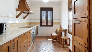 Une cuisine avec des meubles de rangement en bois, un évier, une cuisinière et une fenêtre.