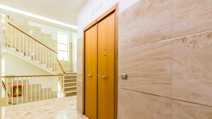 A hallway with a wooden double door, a tiled floor, and a staircase with a railing. - La Dimora Dell Avvocato - Appartamento (Naples)