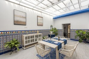 A dining area with a glass ceiling, white walls, and blue and white patterned tiles. - Holiday Home Berraquero (Lantejuela)
