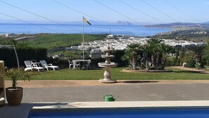 Una piscina amb vistes a una població costanera, una font i gandules.